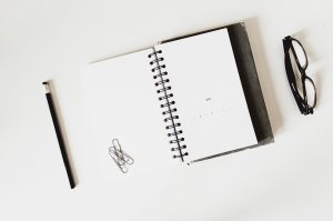 En anteckningsbok och ett par glasögon vid sidan om
