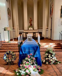 Ett blått bårtäcke på en kista i en kyrka